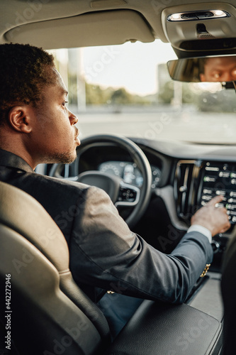 Black businessman inside car using car panel