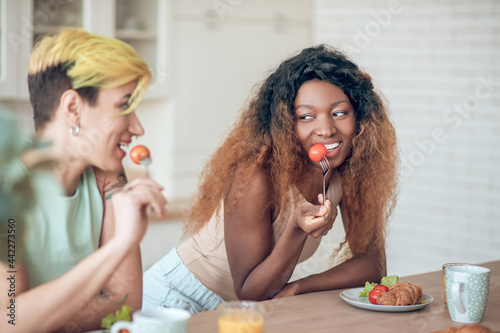 Cute African American woman and girlfriend seductively eating tomato photo