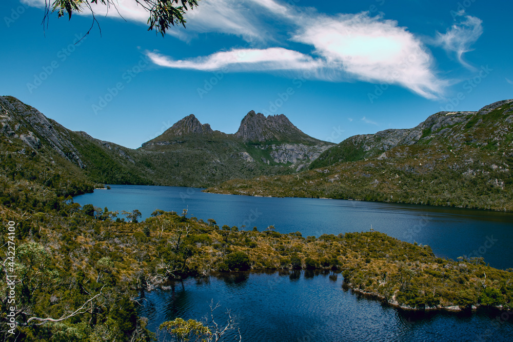 A beautiful view of cradle mountain behind a crystal clear blue lake.