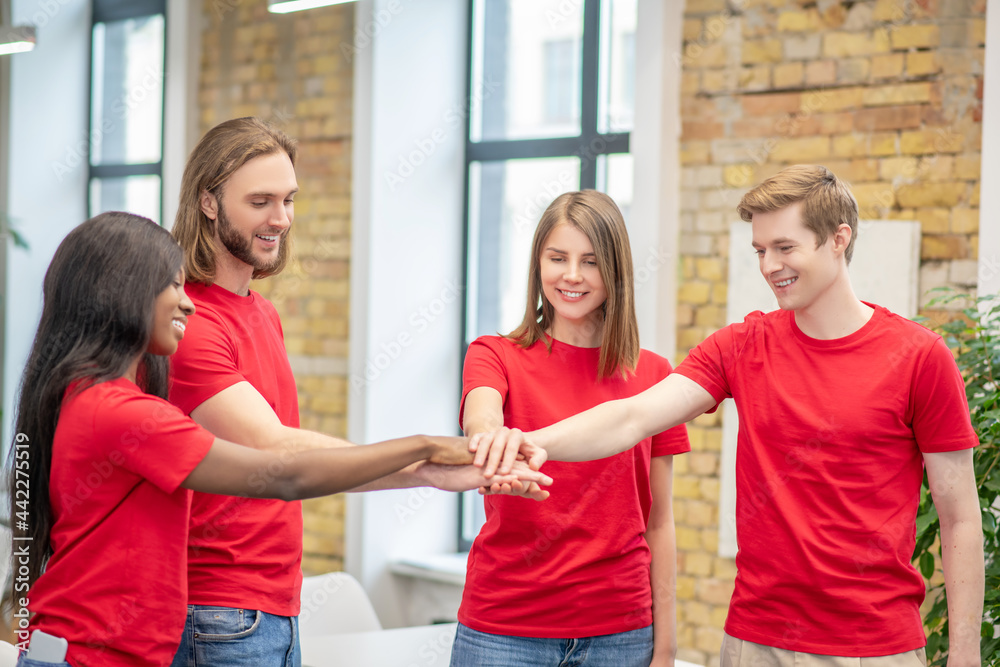 Fototapeta premium Joyful young volunteers showing togetherness gesture
