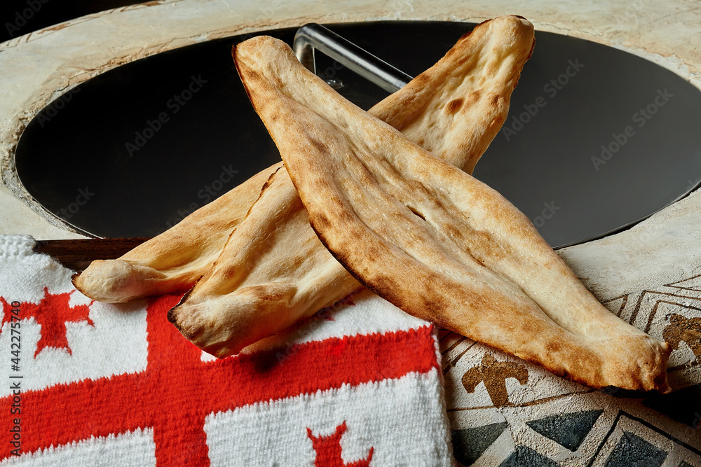 Traditional Georgian bread shotis puri with national flag on tone oven  Photos | Adobe Stock