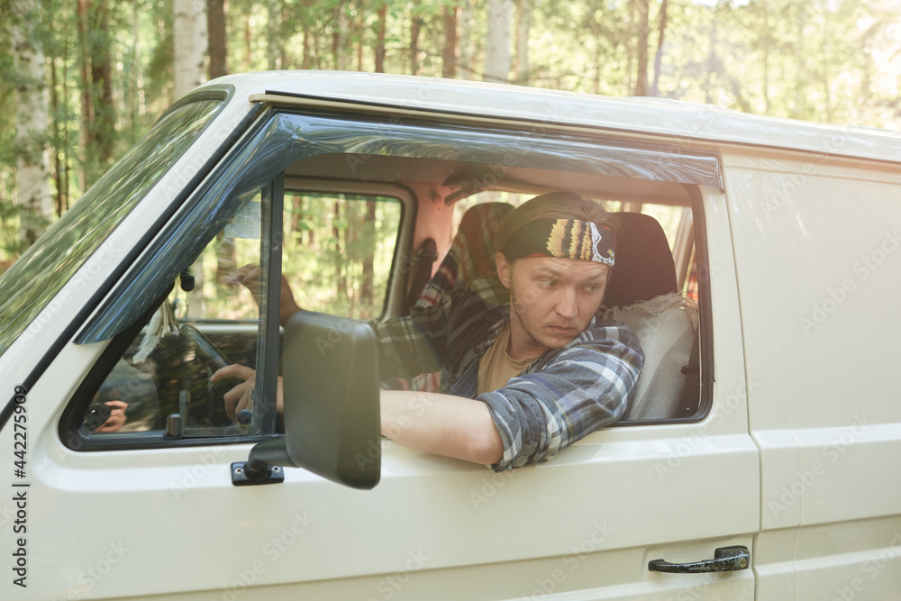 Young man driving by bus along the forest with people in the background Young man driving by bus along the forest with people in the background
