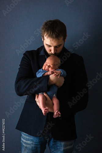 Dad holds a crying newborn in his arms. Happy childhood, selective focus.