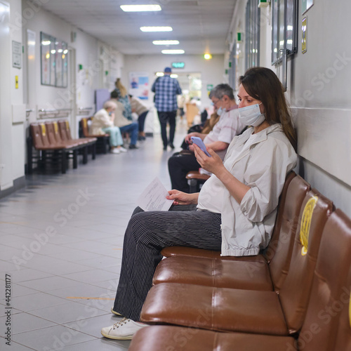 Pregnant woman with phone in hospital corridor with medical mask on face - Moscow, Russia, May 16, 2021 photo