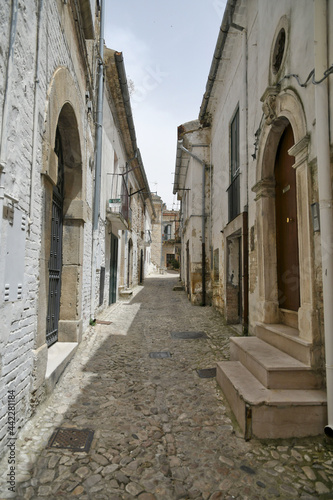 Fototapeta Naklejka Na Ścianę i Meble -  Bovino, Italy, 06/23/2021. A narrow street among the old houses of a medieval town with a Mediterranean style in the Puglia region.