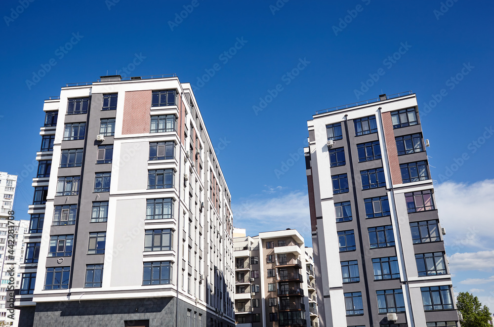 Fototapeta premium Modern European residential apartment buildings quarter on a sunny day with a blue sky. Abstract architecture, fragment of modern urban geometry