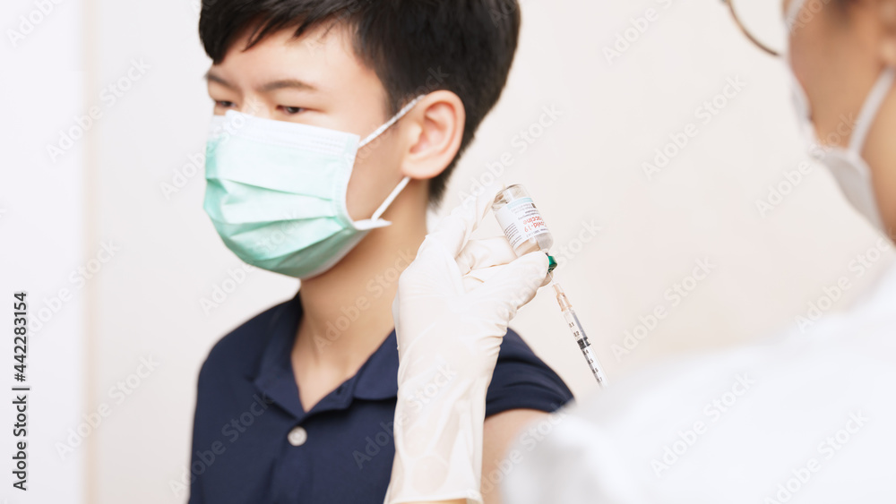 COVID 19 Vaccines for kids and teenager Issue. A smart asian teen boy with medical face mask about to get a vaccine shot at the hospital. Safe, Authorized, Back to school, Insurance, Healthcare.