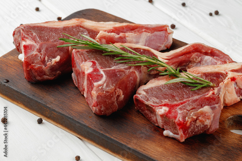 Raw meat ribs on wooden board on white background