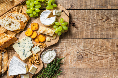 Cheese Board. Brie, Camembert, Roquefort, parmesan and blue cream cheese with grape, fig, bread and nuts on wooden board. wooden background. Top view. Copy space