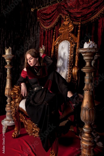 Medieval queen in historical attire on golden throne in castle © Alex Vog