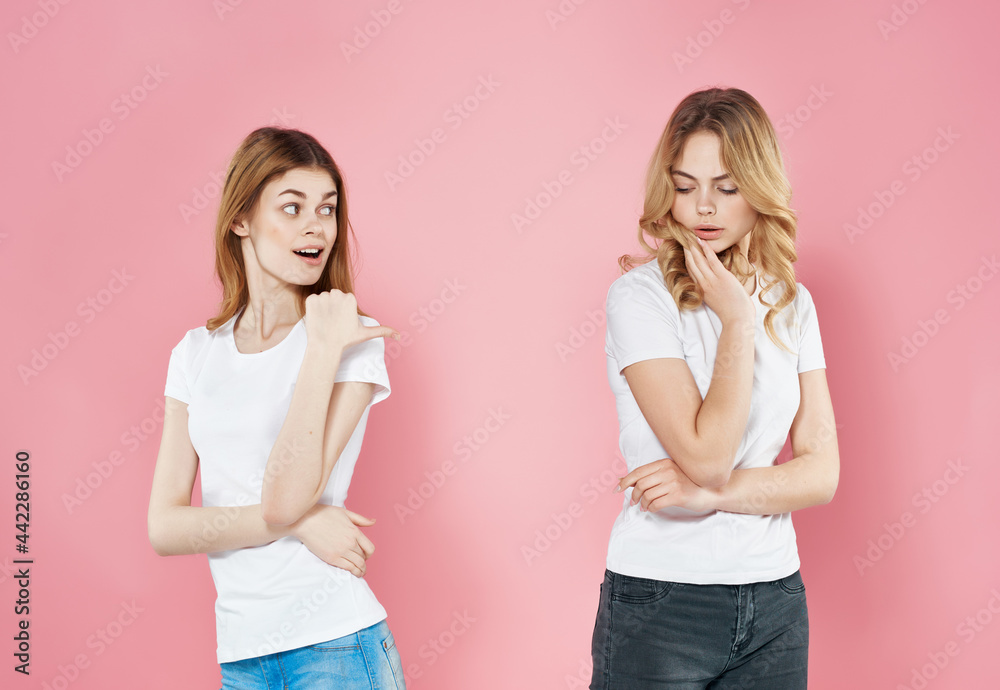two women stand next to each other in white t-shirts friendship emotions pink background two women stand next to each other in white t-shirts friendship emotions pink background