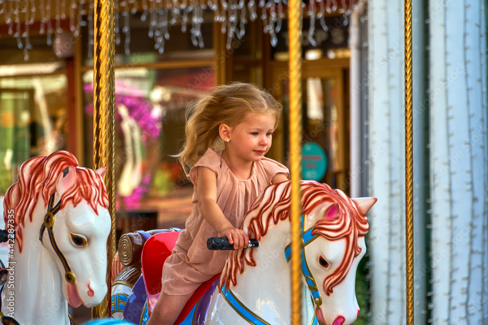 Pretty kid on carousel horse. cute girl is riding attraction. Fun celebration.