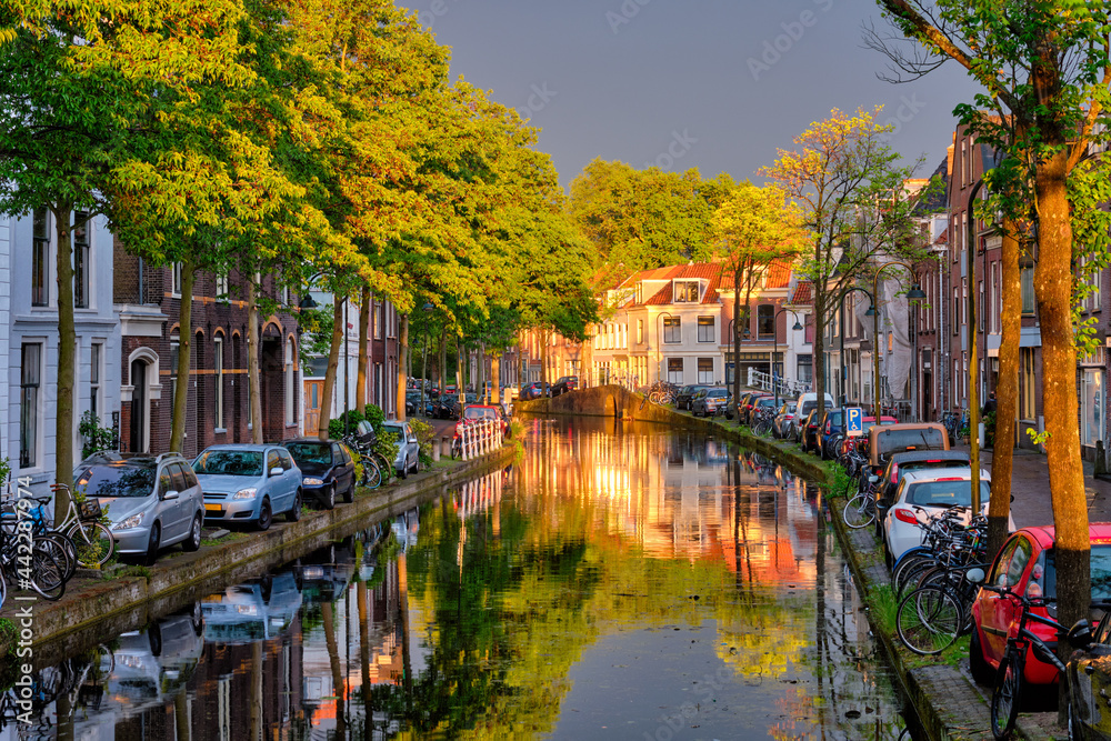 Delt canal with old houses and cars parked along on sunset