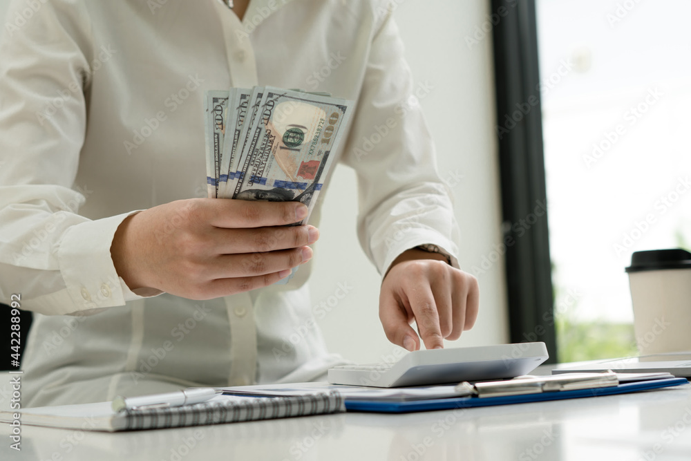 Fototapeta premium Investors are calculating on calculator investment costs and holding cash notes in hand.