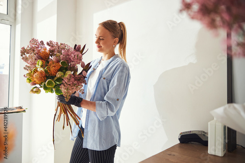 Smiling floral arranger admiring a spring bouquet in her hands photo