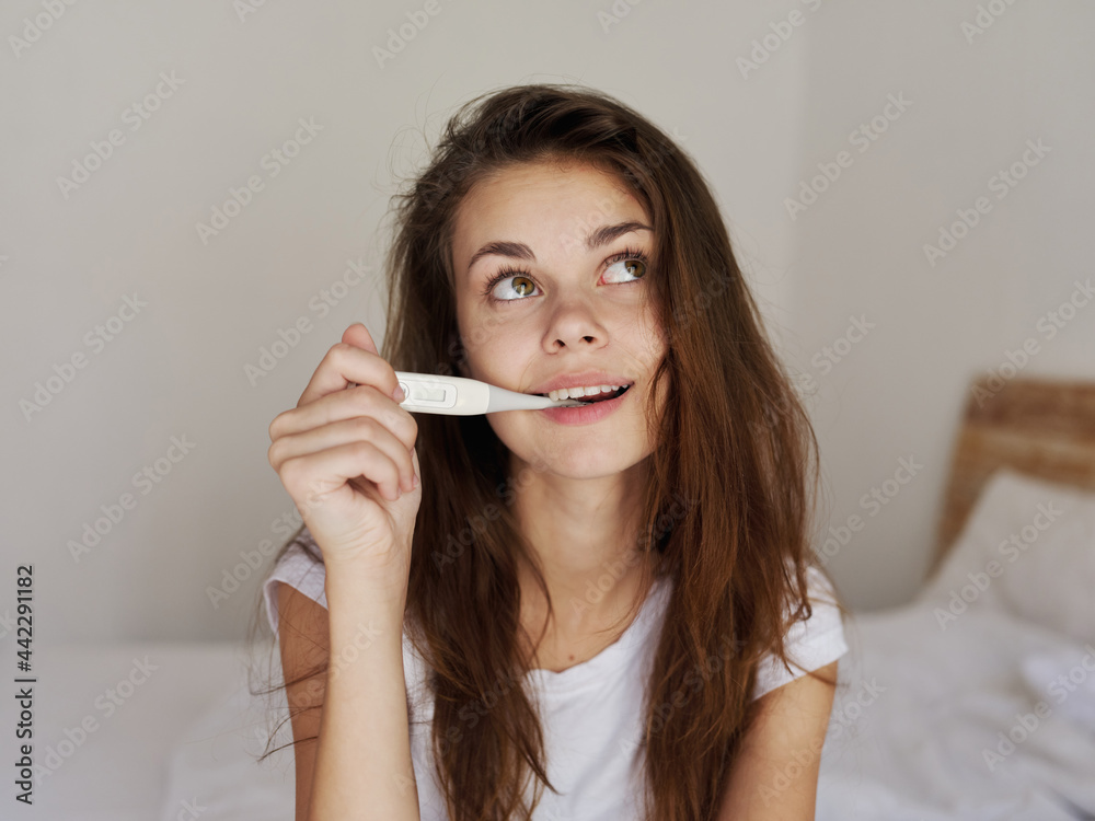 woman with thermometer in mouth looking up checking temperature woman with thermometer in mouth looking up checking temperature