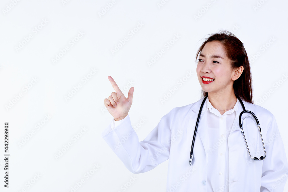 Happy young Asian female medic in uniform with stethoscope pointing aside at blank space on white background while advertising medical service Happy young Asian female medic in uniform with stethoscope pointing aside at blank space on white background while advertising medical service