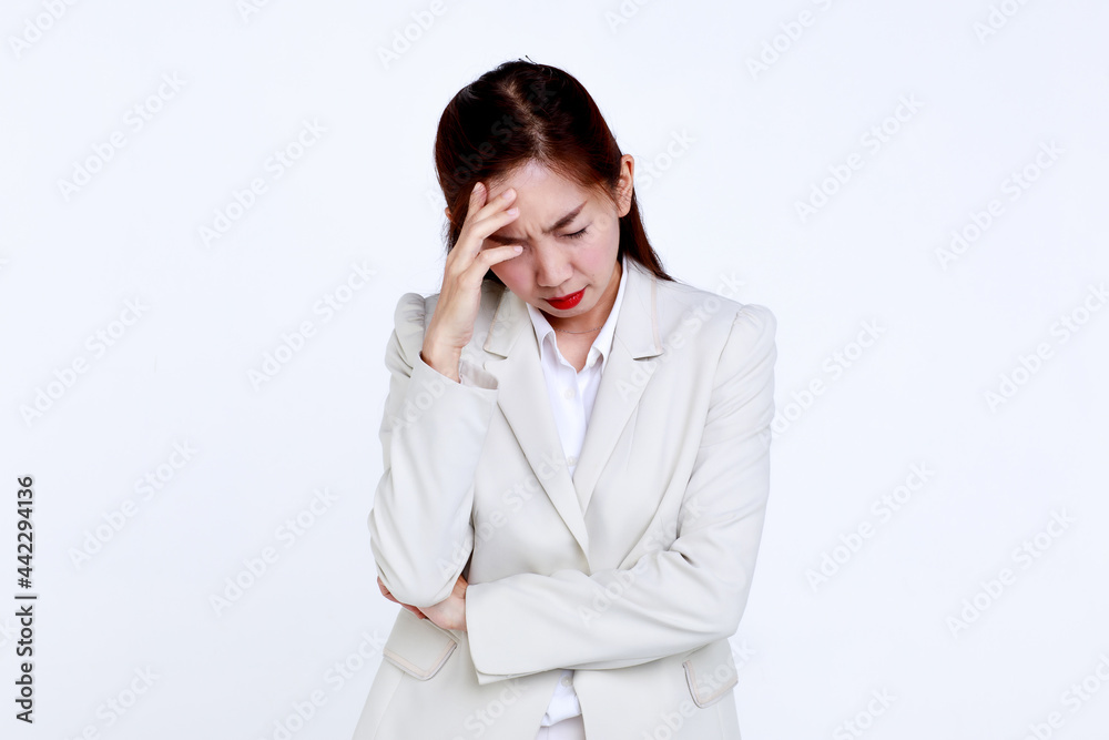 Young Asian businesswoman in formal suit touching forehead while suffering from headache because of business problem against white background Young Asian businesswoman in formal suit touching forehead while suffering from headache because of business problem against white background