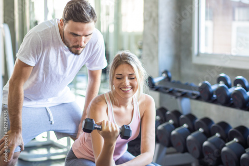 Instructor man teach women lifting up dumbbell in sport gym healthy couple