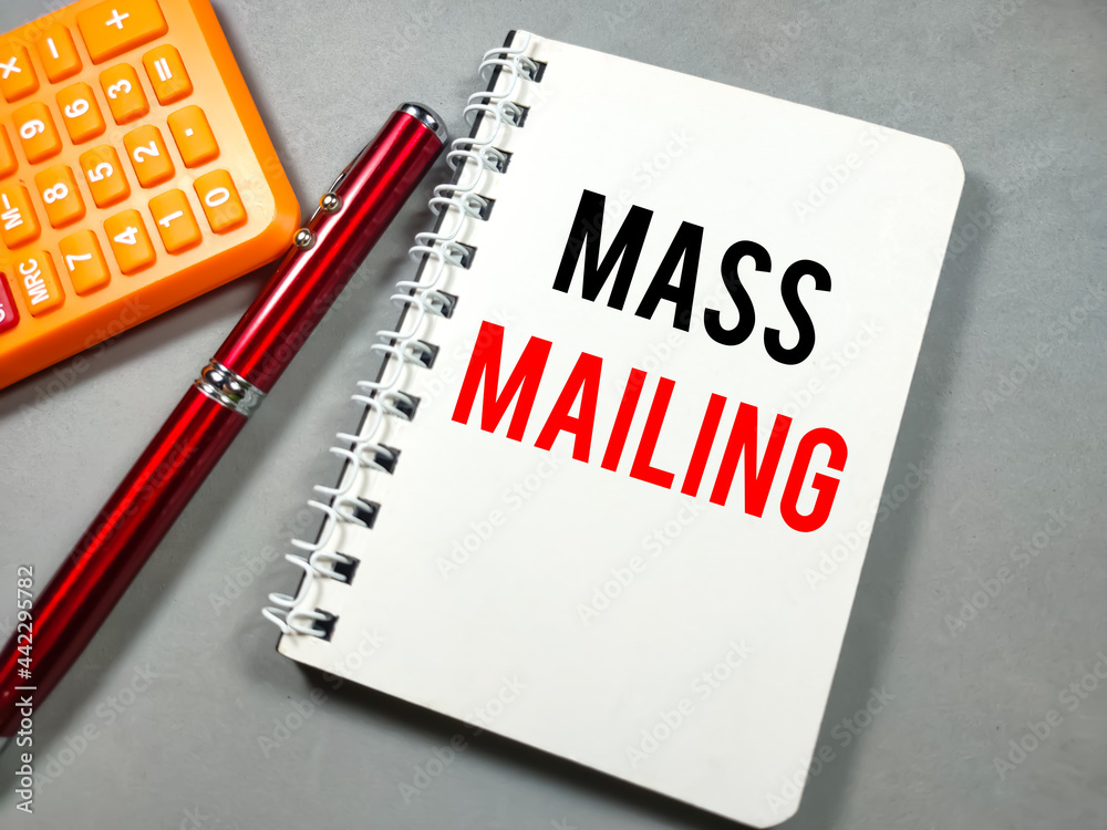 Text MASS MAILING on notebook with pen and calculator on gray background.