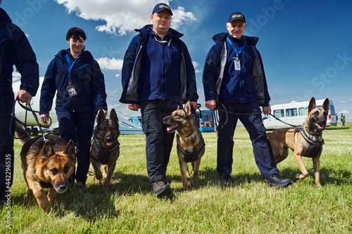 Photography Cheerful security officers with detection dogs walking down airfield