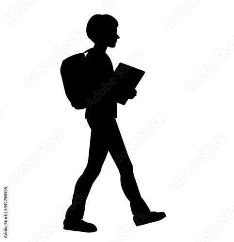 Silhouette of a boy with a school backpack and a book in his hands going to school