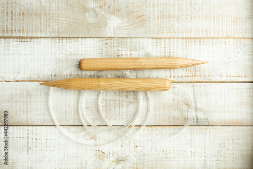 Thick wooden knitting needles for knitting large items with merino wool on a wooden floor