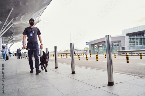 Security officer with detection dog walking outdoors at airport