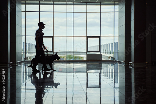 Tableau sur toile Security worker and police dog walking down airport terminal