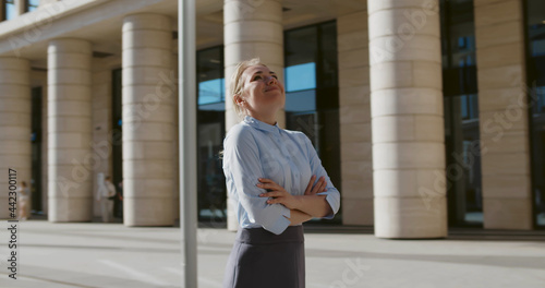 Portrait of young businesswoman with hands crossed standing outside building