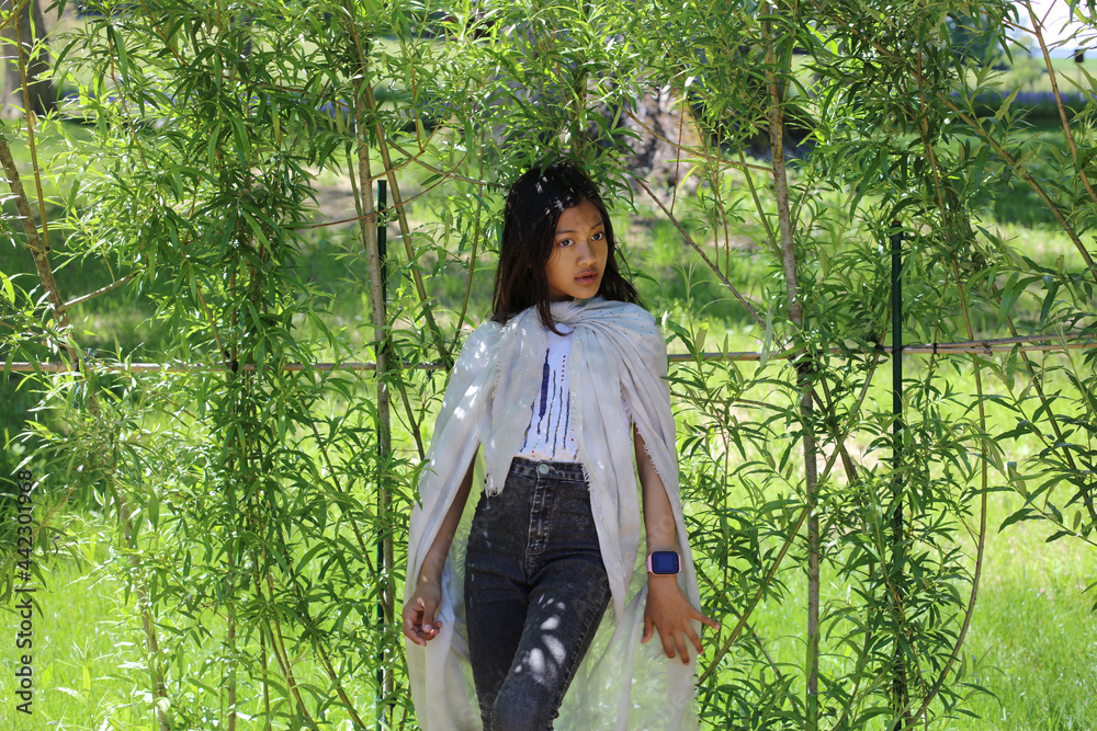 Belle jeune fille asiatique pose devant un décor de verdure