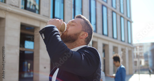 Young confident company owner drinking coffee on his way to office.