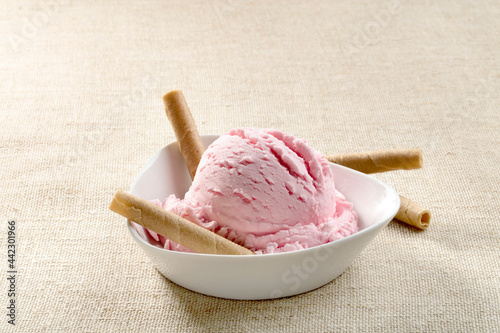 Helado de  fresa con barquillos sobre mantel beige. Strawberry ice cream with waffles on a beige tablecloth. photo