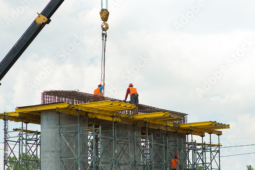 Obraz na płótnie Builders remove cargo from a crane at a construction site w salonie