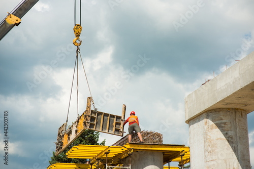 The builder takes the formwork from the crane at the construction site