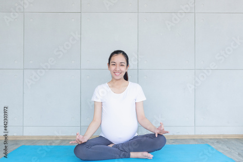 Pregnant asian moms doing yoga and looking at the camera.
