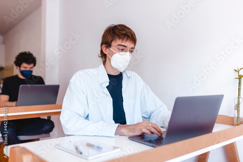 Men wearing protective masks working on their laptop