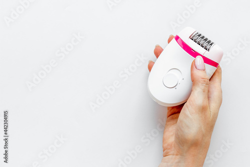 White epilator in female hand for hair removal and depilatory. Top view