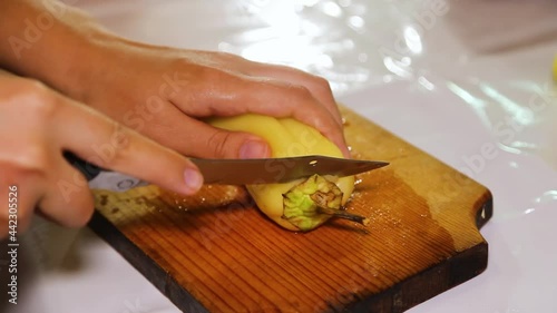 A woman's hand is cutting yellow peppers into cubes on a wooden board. Home cooking vegetables