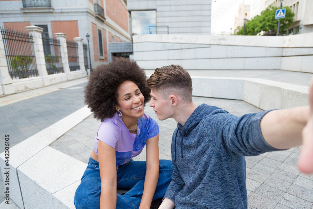 Young afro woman and caucasian man taking a selfie while looking at each other