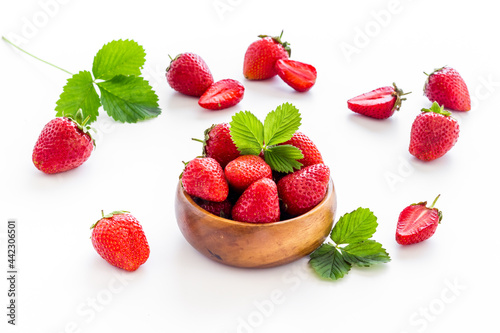 Close up of red strawberry in wooden bowl with leaves