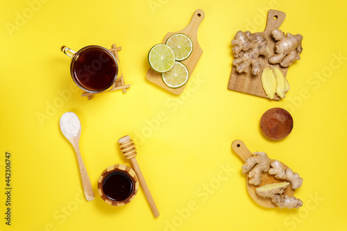 Tea with dried fruits lime, ginger, honey on a yellow background. top view