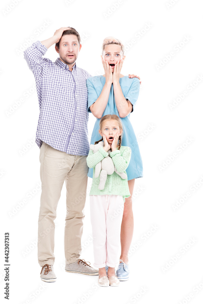 Vertical full length shot of modern man and woman standing with their little daughter astonished at something, white background