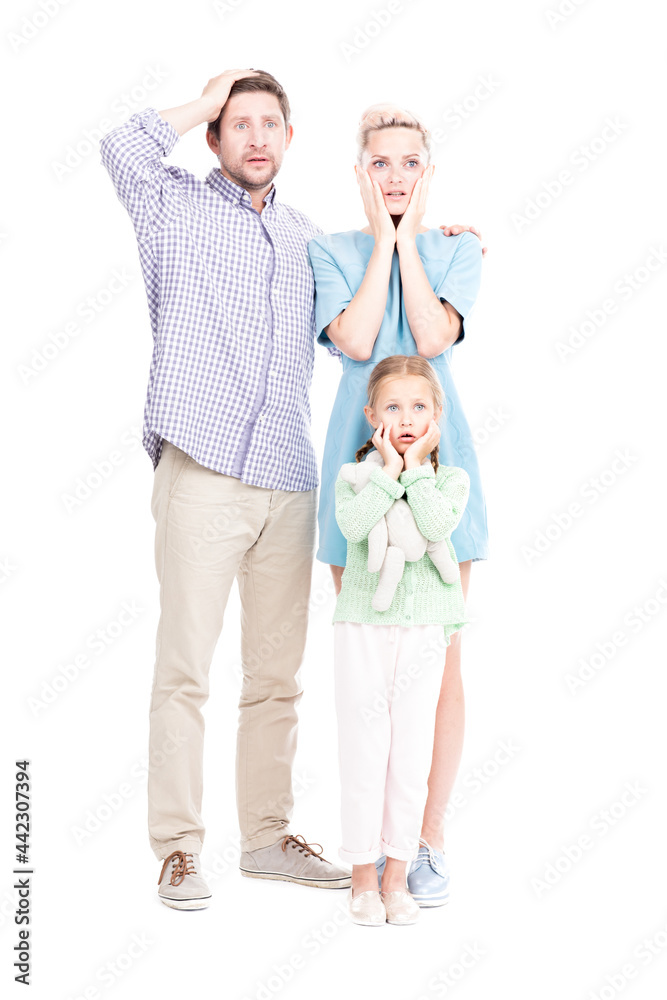 Vertical full length shot of modern man and woman standing with their little daughter astonished at something, white background