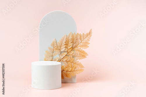 White podium with branch of leaves and arch to show cosmetic products. Beige color background for branding and packaging presentation. photo