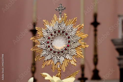 Monstrance (Ostensory) with the Blessed Sacrament (Eucharist) on the Altar of the Church during Eucharistic adoration. The Host bears the inscription JHS, monogram of the name of Jesus photo