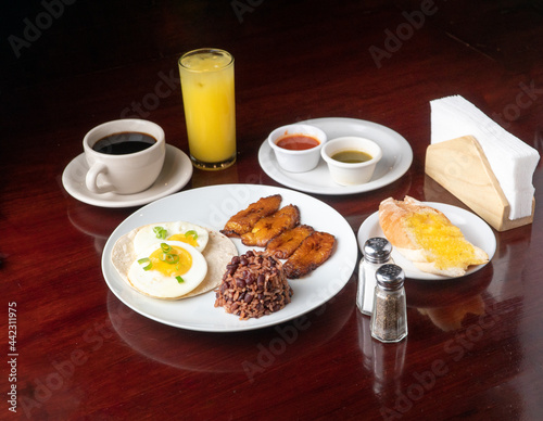 Latin breakfast with all kinds of ingredients like bananas, beans, eggs. coffee and juice to drink 