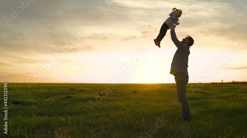 Baby in arms of parent. Dad throws his happy daughter into the blue sky in rays of sun. Father and little child play, laugh and hug together. Happy family travels. Dad day off. Concept of happy family