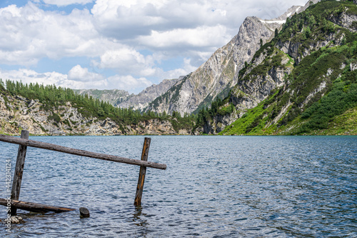 The idyllic Tappenkar Lake in the Austria Alps with a wooden fence reaching into the water