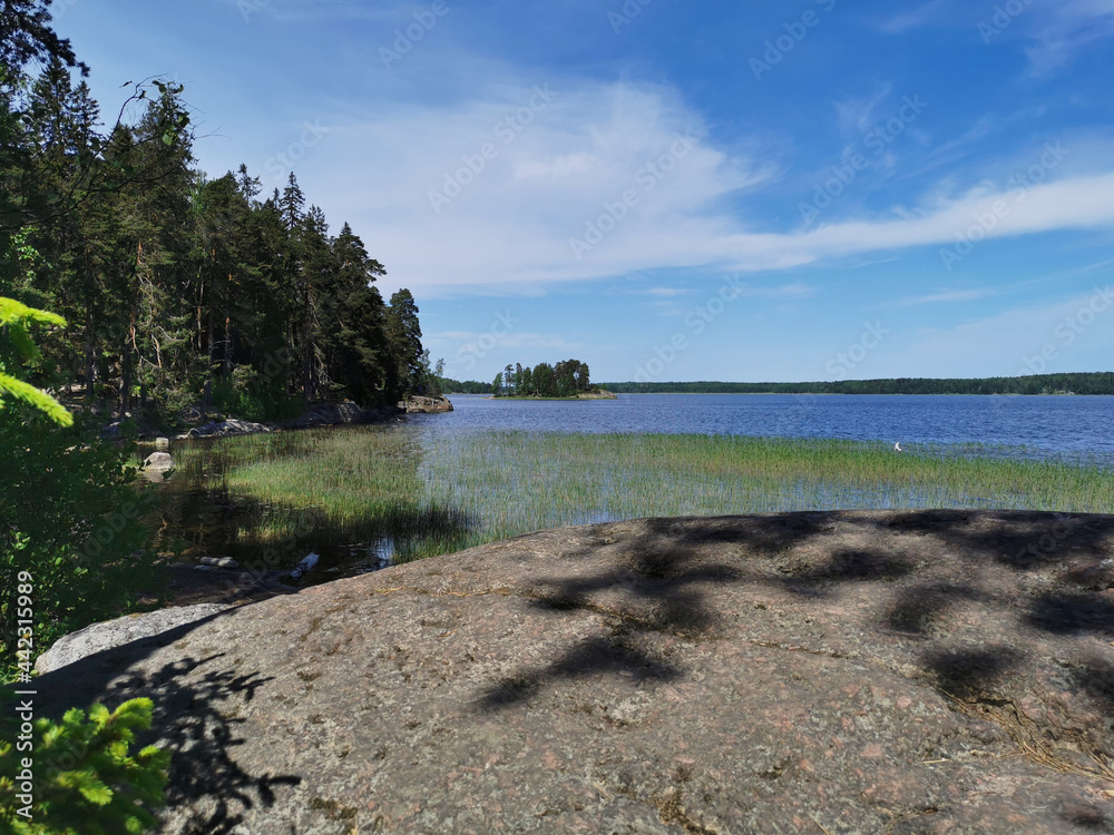 The shore of the Vyborg Bay with large boulders in the rocky natural park Monrepos of the city of Vyborg on a clear summer day.. The shore of the Vyborg Bay with large boulders in the rocky natural park Monrepos of the city of Vyborg on a clear summer day..